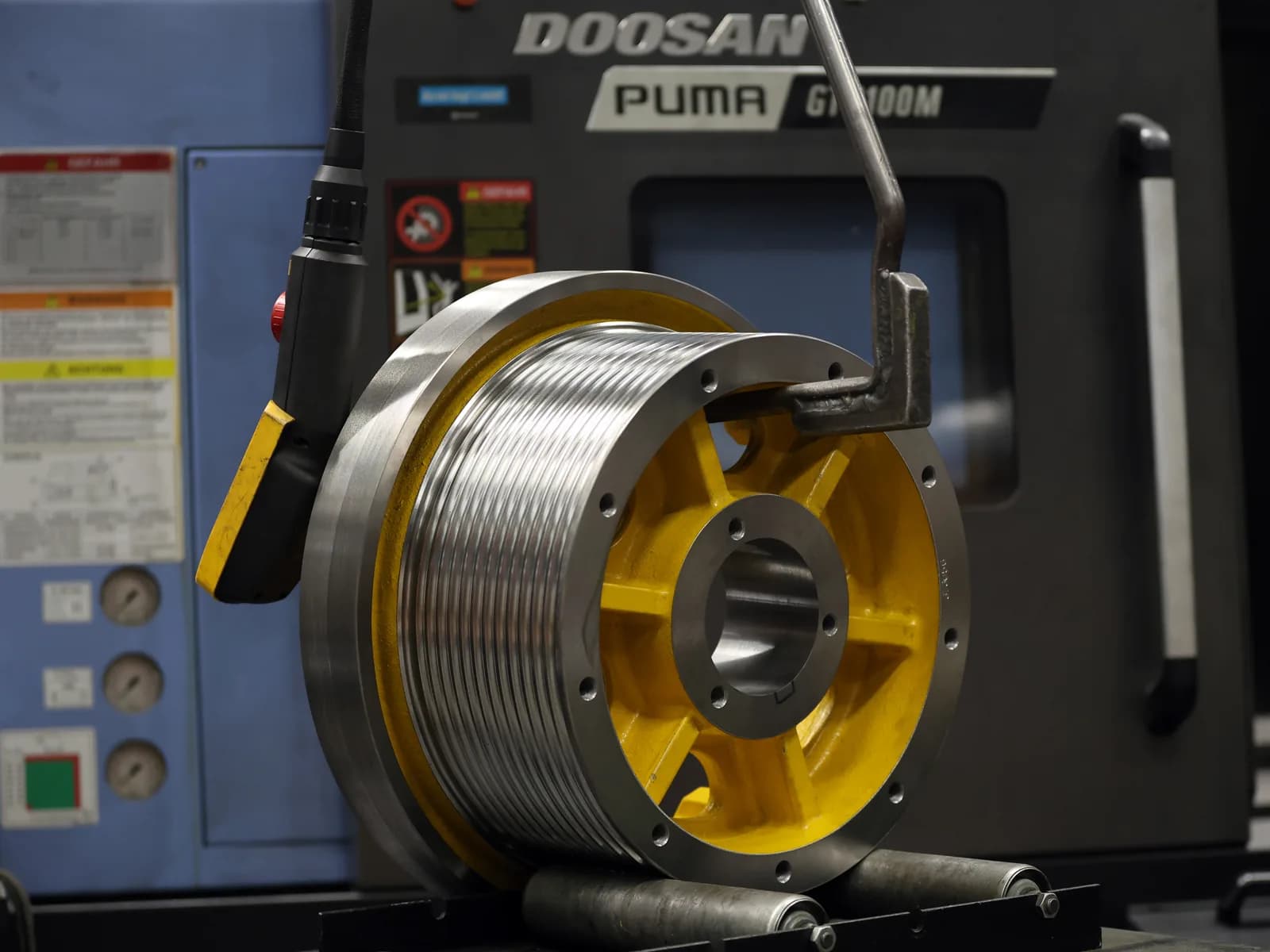 Elevator traction sheave with yellow cast hub on a CNC lathe at FUKA in Cologne