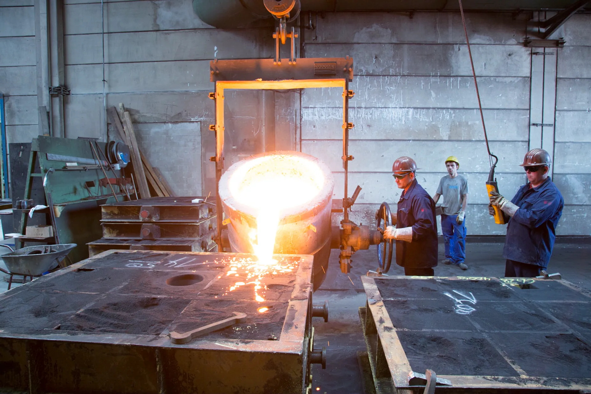 Molten iron being poured from a ladle into a sand mould for elevator sheave castings